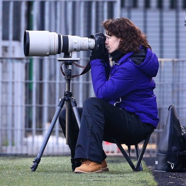Deborah achter fototoestel met grote witte lens.